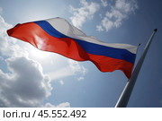 The flag of the Russian Federation on the flagpole proudly flutters in the wind against the backdrop of the blue sky. Стоковое AI-изображение, AI-художник Сергей Елизарьев / Фотобанк Лори