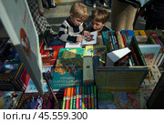 06.04.2023, Москва. Международная ярмарка интеллектуальной литературы «non/fictioNвесна» в Гостином дворе.Маленькие дети рассматривают книгу за прилавком. Редакционное фото, фотограф Дмитрий Киселёв / Фотобанк Лори