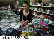 06.04.2023, Москва. Международная ярмарка интеллектуальной литературы «non/fictioNвесна» в Гостином дворе. Девушка за прилавком с книгами. Редакционное фото, фотограф Дмитрий Киселёв / Фотобанк Лори