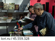 06.04.2023, Москва. Международная ярмарка интеллектуальной литературы «non/fictioNвесна» в Гостином дворе. Мужчины смотрят книги на прилавке. Редакционное фото, фотограф Дмитрий Киселёв / Фотобанк Лори