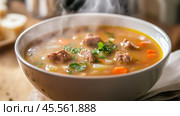Steaming hot bowl of beef and vegetable soup garnished with fresh parsley. Стоковое AI-изображение, AI-художник Юрий Поздников / Фотобанк Лори