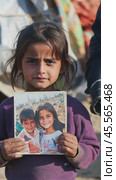 Young refugee girl showing photo of friends in camp. Стоковое AI-видео, аниматор Юрий Поздников / Фотобанк Лори