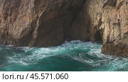 Sea waves enter a cave in rock and form splashes. Стоковое видео, видеограф Михаил Коханчиков / Фотобанк Лори
