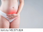 Pregnant woman with abdominal pain, risk of premature birth, gray background. Стоковое фото, фотограф Станислав Тарко / Фотобанк Лори