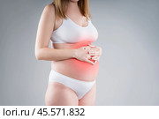 Pregnant woman with abdominal pain, risk of premature birth, gray background. Стоковое фото, фотограф Станислав Тарко / Фотобанк Лори