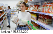 Young woman in supermarket buys daily groceries, pasta Chinese noodles. Стоковое видео, видеограф Яков Филимонов / Фотобанк Лори