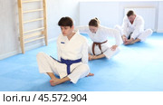 Athletes before training martial arts performs stretching butterfly pose to warm up muscles. Стоковое видео, видеограф Яков Филимонов / Фотобанк Лори