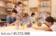 Interested children of different ages painting ceramic objects with teacher in art studio. Стоковое видео, видеограф Яков Филимонов / Фотобанк Лори