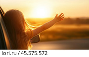 Child enjoys sunset from car window while extending arm joyfully toward the horizon at golden hour. Стоковое AI-изображение, AI-художник Сергей Толмачёв / Фотобанк Лори