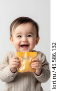 Happy baby enjoying squeezable food pouch for mealtime fun and nutrition. Стоковое AI-изображение, AI-художник Sabyna75 / Фотобанк Лори