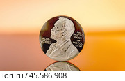 Moscow December 03 2024. Close-up of Alfred Nobel's engraving on coin. Nobel Peace Prize concept. Nobel Prize award. Редакционное фото, фотограф Скрипачев Антон / Фотобанк Лори