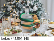 A green snake, the symbol of 2025 according to the Eastern calendar, is wrapped around a fogged decanter on the festive table. Стоковое AI-изображение, AI-художник Сергей Комаров / Фотобанк Лори