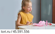 A little girl paints her cheeks with baby blush. The child draws with children's cosmetics. A daughter imitates her mother. Стоковое фото, фотограф Кутина Татьяна / Фотобанк Лори
