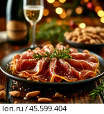 Thin slices of jamon. Jamon (in Spanish jamon - "ham") is a national dish of Spain, a dry-cured pork leg. Only the hind legs of the pig are used for jamon, which are dried whole. Enjoy your meal! Стоковое AI-изображение, AI-художник Сергей Елизарьев / Фотобанк Лори