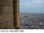 Top view of the ancient city from the loophole of the fortress. The Caspian Sea stretches beyond the houses of the city of Derbent. View of the old quarters of Derbent from the Naryn-Kala fortress. Стоковое фото, фотограф Эдуард Белкин / Фотобанк Лори