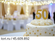 50th birthday cake adorned a gold accents. Birthday party. Blurred light festive background. Golden balloons. Fifty years, Fiftieth anniversary. Celebration cake, golden candles. Numbers 50. Стоковое AI-изображение, AI-художник Марина Демидюк / Фотобанк Лори