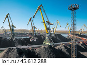 Горы угля в морском порту, грузовые вагоны из под угля, телескопические ленточные транспортеры, которые перераспределяют уголь по участку. Стоковое фото, фотограф Павел Просянов / Фотобанк Лори