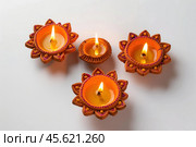 Burning diyas celebrating diwali festival on white background. Стоковое AI-изображение, AI-художник Иван Рябоконь / Фотобанк Лори