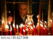 16.04.2023, Истра. Мужчина-прихожанин ставит свечу в кандило во время Пасхальной службы в Cтавропигиальном Воскресенском Новоиерусалимском мужском монастыре Русской православной церкви. Редакционное фото, фотограф Дмитрий Киселёв / Фотобанк Лори
