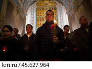 16.04.2023, Истра. Молодой мужчина с горящими свечами в руке во время Пасхальной службы в Cтавропигиальном Воскресенском Новоиерусалимском мужском монастыре Русской православной церкви. Редакционное фото, фотограф Дмитрий Киселёв / Фотобанк Лори