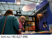 Женщина с ребёнком на книжной выставке (2022 год). Редакционное фото, фотограф Дмитрий Киселёв / Фотобанк Лори