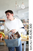Man buys food for Christmas dinner. Guy is interested choosing snacks and alcohol for the New Year's party. Стоковое видео, видеограф Яков Филимонов / Фотобанк Лори