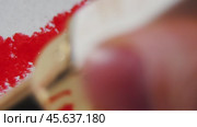 A mesmerizing close-up showcasing the creation of abstract art. A hand delicately applies lipstick to white cardboard, forming swirling, vibrant patterns. Стоковое видео, видеограф Ярославский Максим / Фотобанк Лори