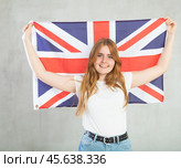 smiling girl in arms raised above head holds canvas of national British flag. Стоковое фото, фотограф Яков Филимонов / Фотобанк Лори
