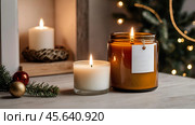 A mock-up of a cozy burning candle made of amber glass with an empty white label in a festive, New Year's home interior. Стоковое AI-изображение, AI-художник Photojuli / Фотобанк Лори
