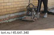 Worker using vibrating soil compactor for sand ramming. Construction and renovation. Стоковое видео, видеограф Мария Зубарева / Фотобанк Лори