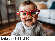 A cute little girl in stylish red heart-shaped glasses, having fun celebrating Valentine's Day. Стоковое AI-изображение, AI-художник Photojuli / Фотобанк Лори