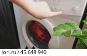 Woman in orange apron turns on washing machine, modern washing machines with smart features and functions. Стоковое видео, видеограф Svetlana Golovco / Фотобанк Лори