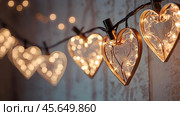 The concept of Valentine's Day, a banner with garlands in the form of hearts and magic lights for a holiday filled with love. A place for the text. Стоковое AI-изображение, AI-художник Photojuli / Фотобанк Лори