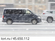 Black Volkswagen Multivan T6 riding at winter city street during snowfall. Редакционное фото, фотограф Константин Григорьев / Фотобанк Лори