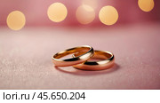 Gold wedding rings on a pink background with a side. Wedding rings. The wedding day. The newlyweds. Стоковое AI-изображение, AI-художник Photojuli / Фотобанк Лори