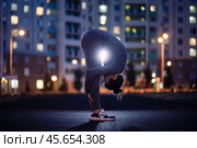 Спортивная девушка делает растяжку вечером во дворе жилого комлпекса. Женщина делает зарядку. Забота о здоровье. Стоковое фото, фотограф Евгений Зимин / Фотобанк Лори
