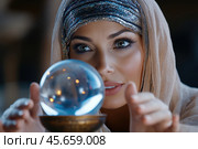 Gypsy fortune teller predicts fate by looking into a crystal ball. Стоковое AI-изображение, AI-художник Евгений Харитонов / Фотобанк Лори
