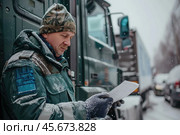 A transport inspection officer checks cargo transportation documents and inspects trucks. Customs point. Inspection. Стоковое AI-изображение, AI-художник Коханова Наталья / Фотобанк Лори