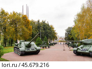 Посетители прогуливаются по городскому парку, где расположены несколько танков и пушек. Осень, деревья покрыты желтыми листьями, погода облачная и прохладная. Редакционное фото, фотограф Сергей Никифоров-Гордеев / Фотобанк Лори