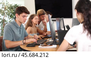Focused young guy studying in computer lab with fellow students engrossed in coursework. Стоковое видео, видеограф Яков Филимонов / Фотобанк Лори