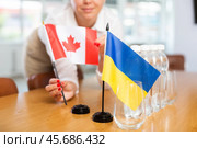 Female office coordinator setting flags of Ukraine and Canada on table. Стоковое фото, фотограф Яков Филимонов / Фотобанк Лори