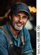 Smiling craftsman wearing work clothes with a rustic background captured in daylight outdoors. Стоковое AI-изображение, AI-художник Юлия Гапеенко / Фотобанк Лори