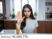 Young woman refusing alcoholic beverage at home, promoting healthy lifestyle and sobriety. Стоковое AI-изображение, AI-художник Иван Рябоконь / Фотобанк Лори