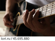 Playing the guitar. Strumming acoustic guitar. Musician plays music. Man fingers holding mediator. Man hand playing guitar neck in dark room. Unrecognizable person rehearsing, fretboard close-up. Стоковое фото, фотограф Марина Демидюк / Фотобанк Лори