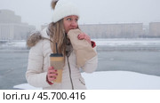 Молодая женщина ест сладкий крендель на улице во время снегопада. Уличная еда. Зима. Стоковое видео, видеограф Терехова Марина / Фотобанк Лори