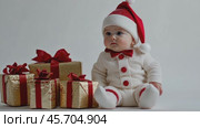 Baby in festive attire sitting with wrapped gifts and christmas decorations. Стоковое AI-видео, аниматор Sabyna75 / Фотобанк Лори