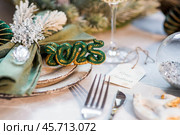 Stylish plates, napkin, glass, champagne, Christmas tree branches and Christmas decorations on a gray background. Table setting. The concept of Merry Christmas and New Year 2025. Стоковое фото, фотограф Photojuli / Фотобанк Лори