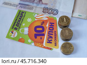 Купон на скидку и десятирублевые монеты сложенные в столбики. Редакционное фото, фотограф Сергей Овчинников / Фотобанк Лори