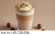 Mockup. Hot hazelnut coffee on a pale beige background. Space for text. Spice Latte or cappuccino. A rich and creamy hazelnut latte with a crumb of crushed nuts, served in a clear glass. Стоковое AI-видео, аниматор Марина Демидюк / Фотобанк Лори