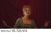 A beautiful singer, wearing an expensive, shiny dress with sequins and beautiful jewelry around her neck, is engaging in vocals. Стоковое видео, видеограф Strunov David / Фотобанк Лори
